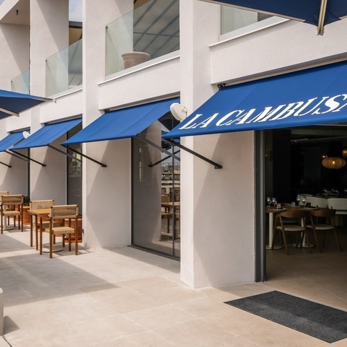 a restaurant with a blue awning that says la cambusa