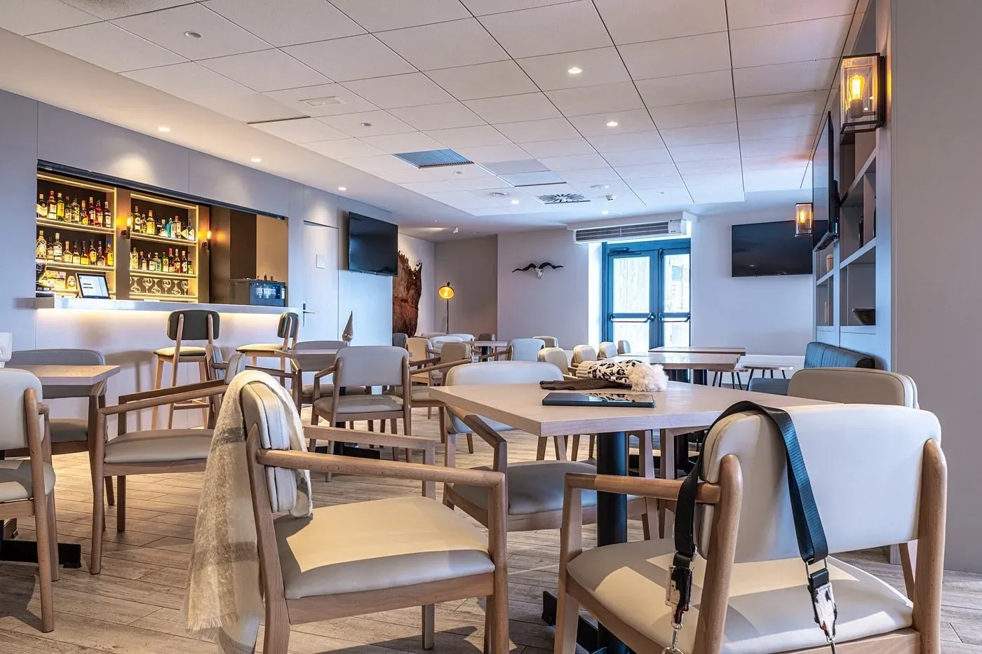 Interior d'un hotel amb bar i taules de menjador, Serveis | Apartaments Caribou | Estival Group | Web Oficial