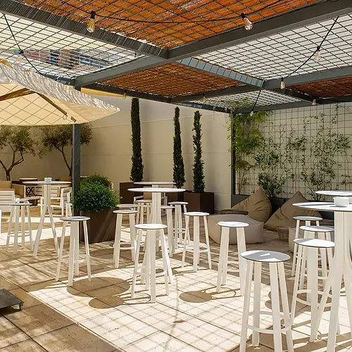 Hotel Vilamari Barcelona: chic outdoor patio with white bar stools and tables.
