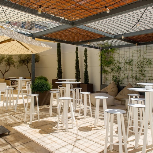 a patio with tables and stools under an umbrella