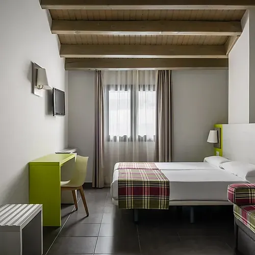 Modern hotel room with twin beds, desk, and TV. Hotel Cristina | Andorra | Estival Group | Official Web.