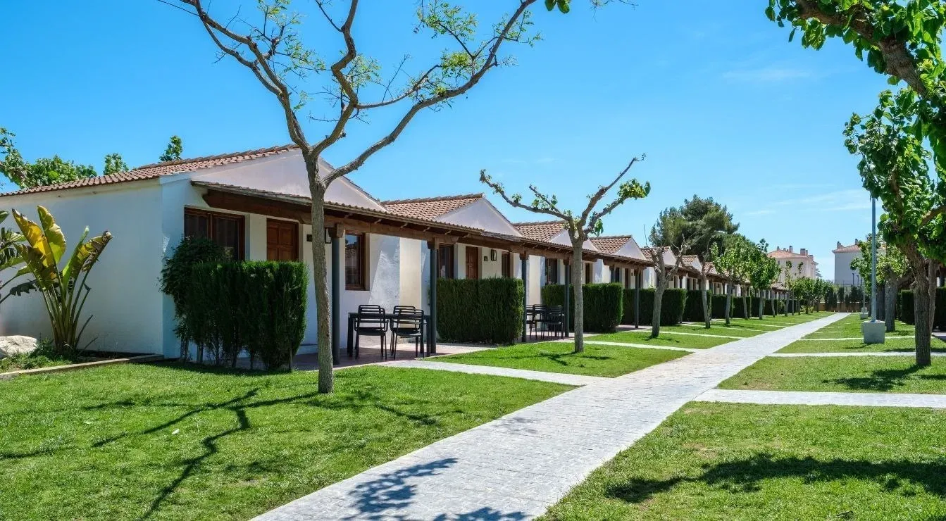Allotjaments Estival Vendrell Platja: bungalows blancs amb terrasses i camí pavimentat.