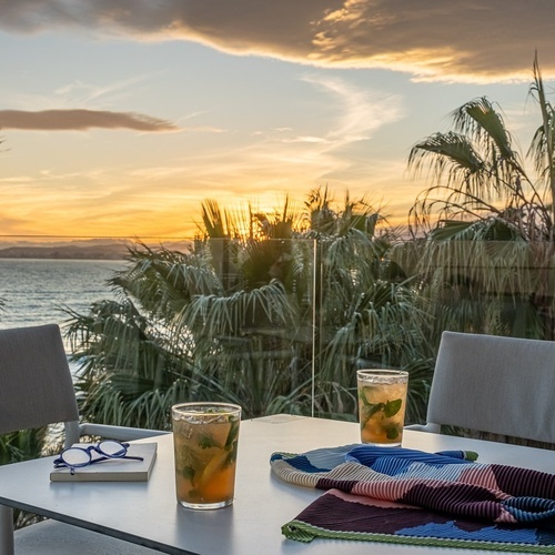 two drinks on a table with a sunset in the background