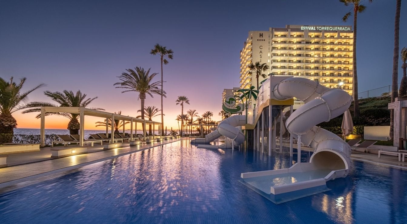 a sunset over the ocean with a swimming pool in the foreground