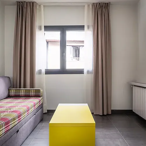 Modern hotel room with sofa, yellow desk, and TV. Hotel Cristina | Andorra | Estival Group | Official Web