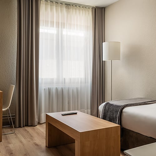 Modern hotel room with twin beds, ski art, and scenic mountain views at Hotel Sporting Andorra | Grandvalira Pas de la Casa.