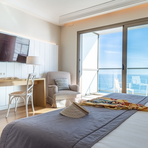 a hotel room with a large bed a chair and a flat screen tv