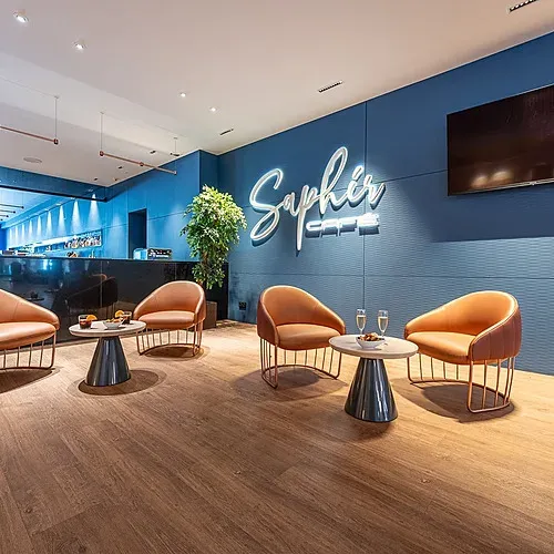 Saphir Cafe lounge area at Estival Torrequebrada Benalmádena: stylish seating, neon sign, TV.
