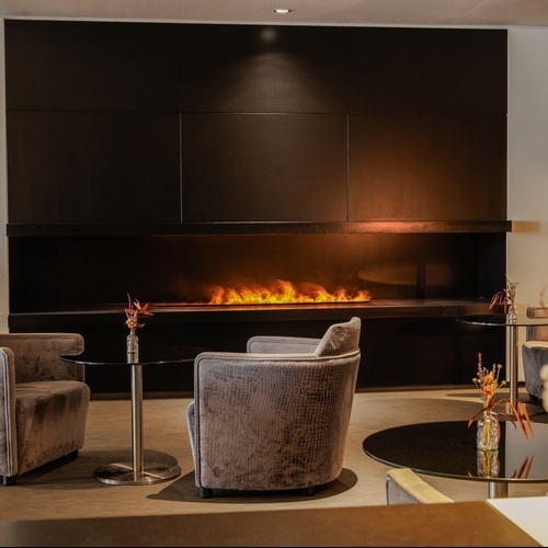 a living room with chairs and tables and a fireplace
