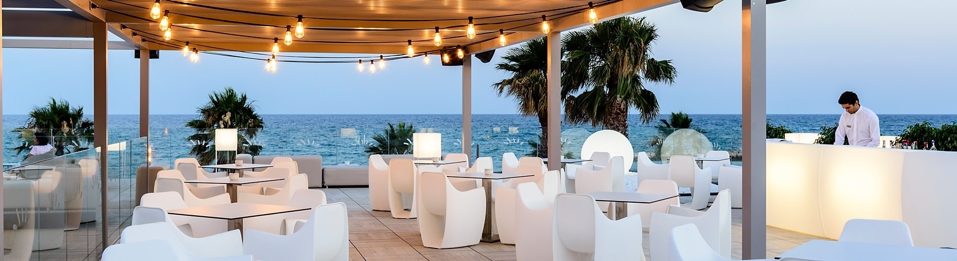 a view of the ocean from a restaurant with tables and chairs