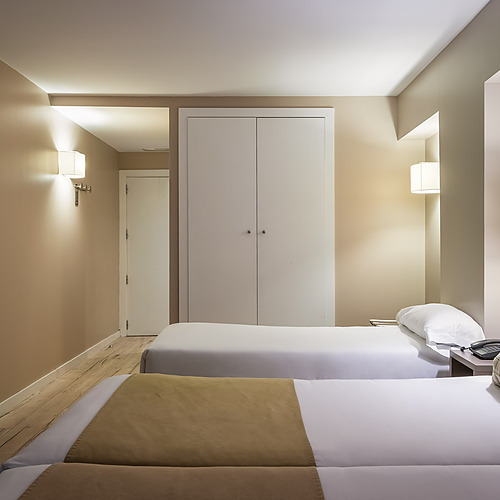 Twin ESTIVAL: Corporativa rooms with modern decor, wood-paneled accent wall, and bedside lamps.