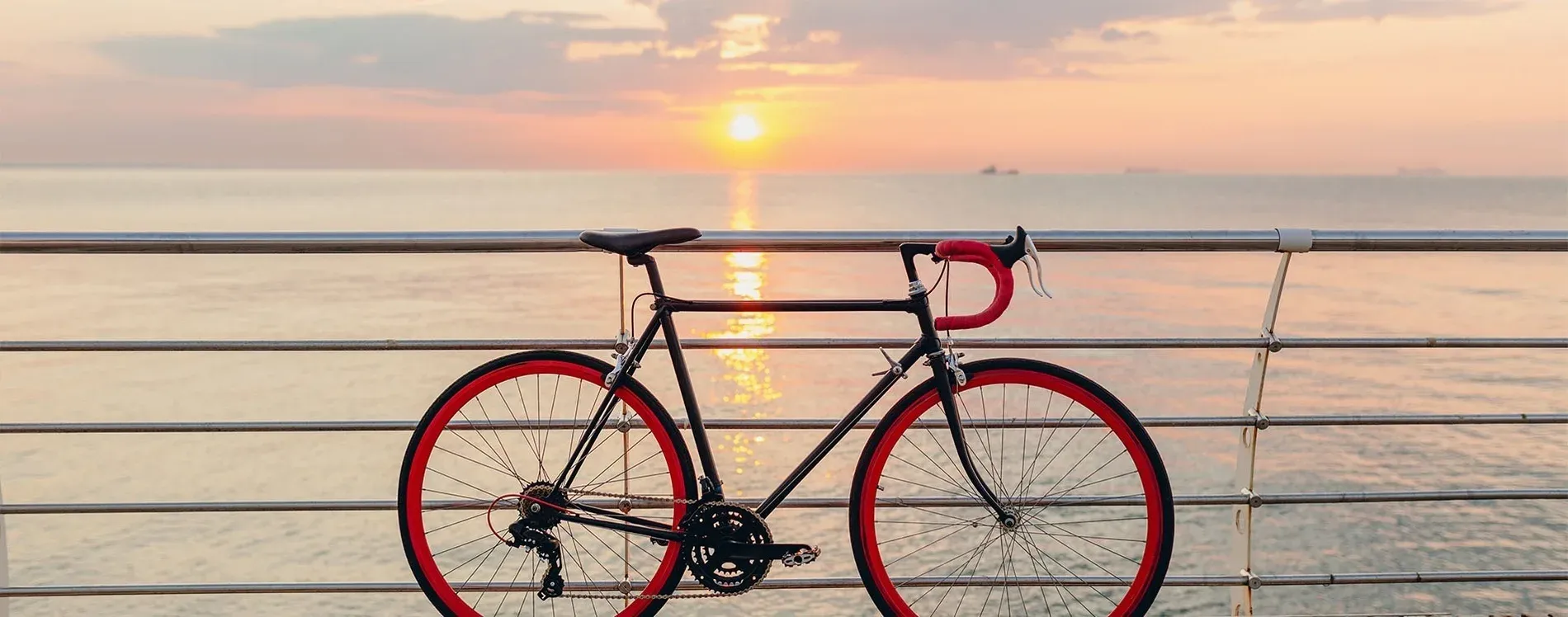 Bicicleta de carretera con ruedas rojas al amanecer, perfecta para cicloturismo en Málaga con Estival Group.