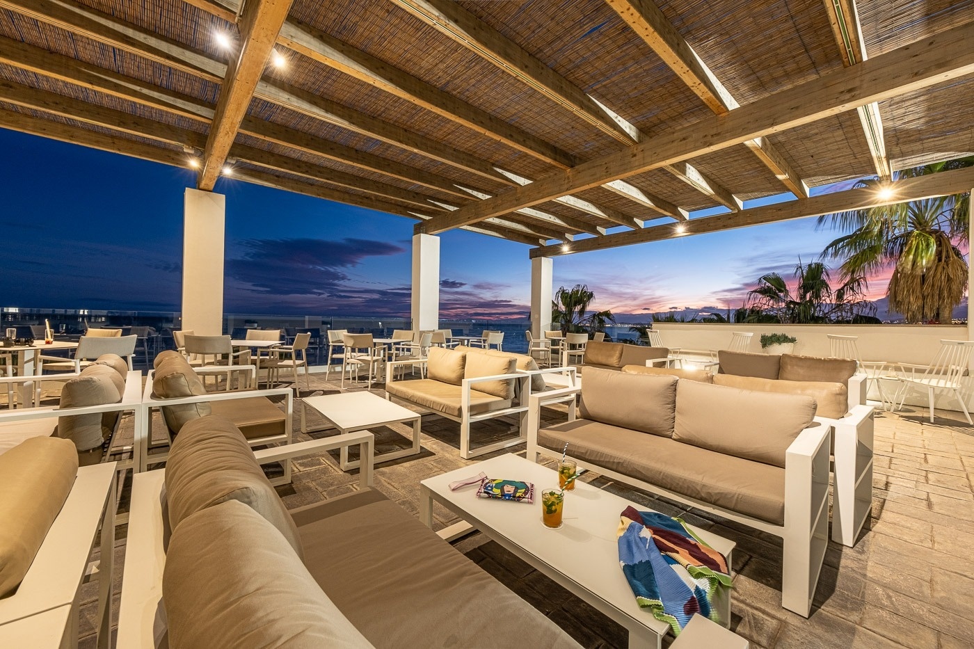 un patio con muchos sofás y mesas al atardecer