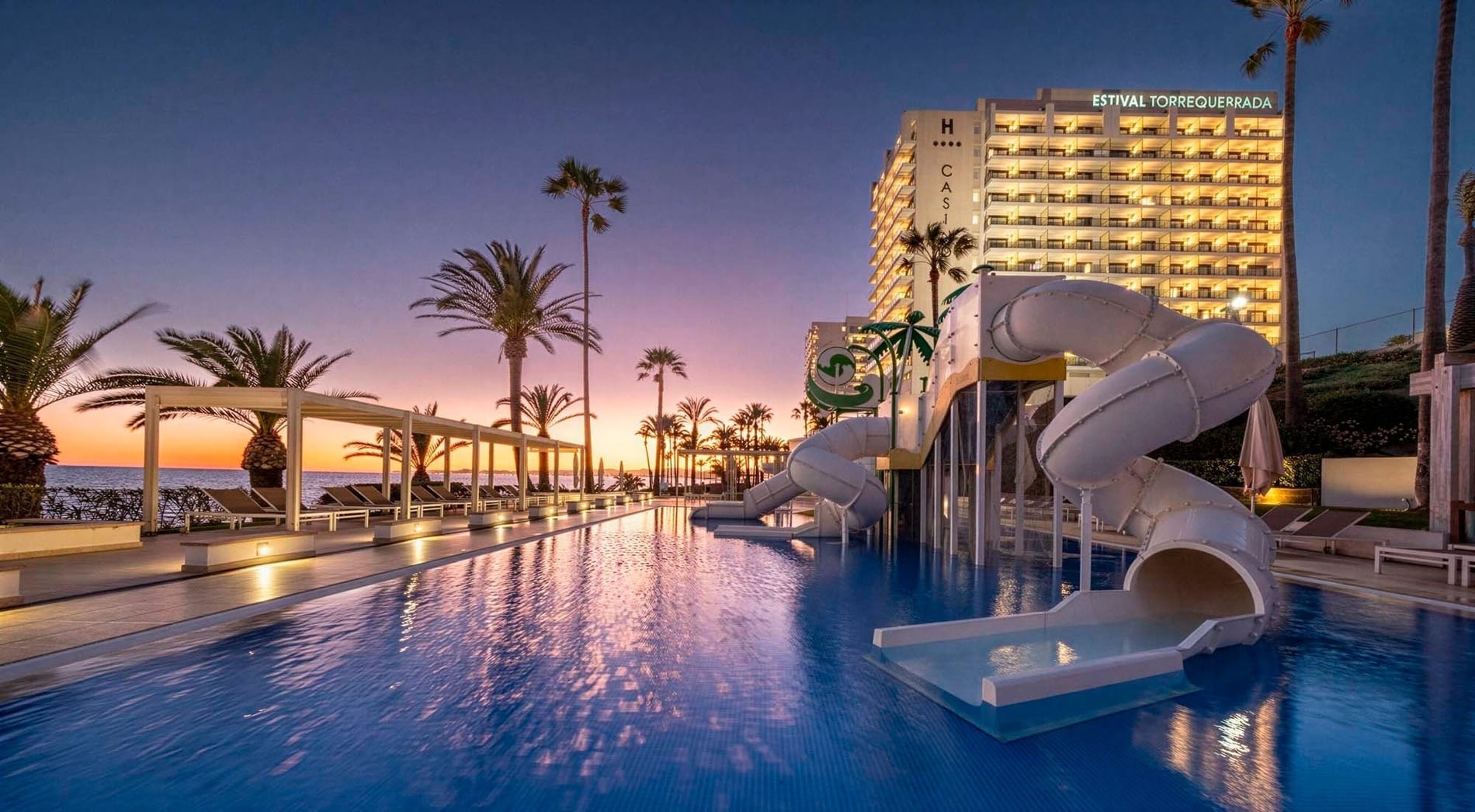 a sunset over the ocean with a swimming pool in the foreground
