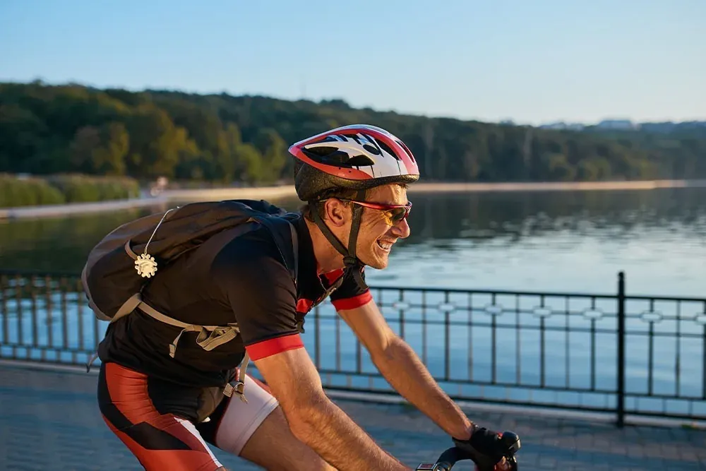 Ciclista sonriente con casco y mochila, ideal para eventos ESTIVAL: Corporativa.