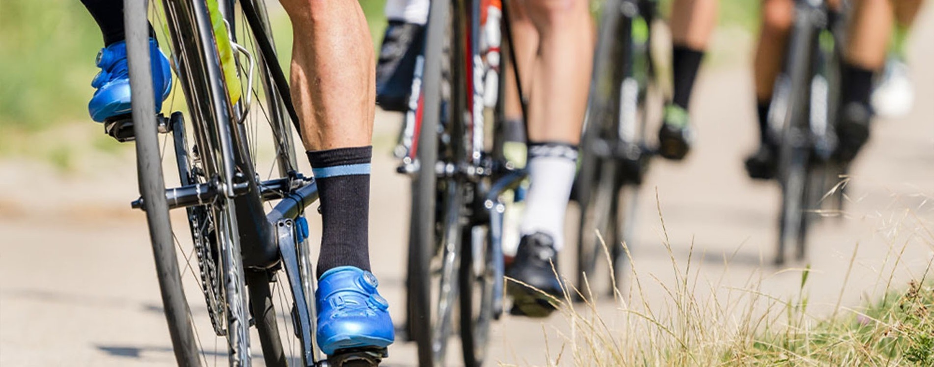 Una bicicleta negra con ruedas y manillar rojos se apoya en una barandilla metálica frente al mar al atardecer.
