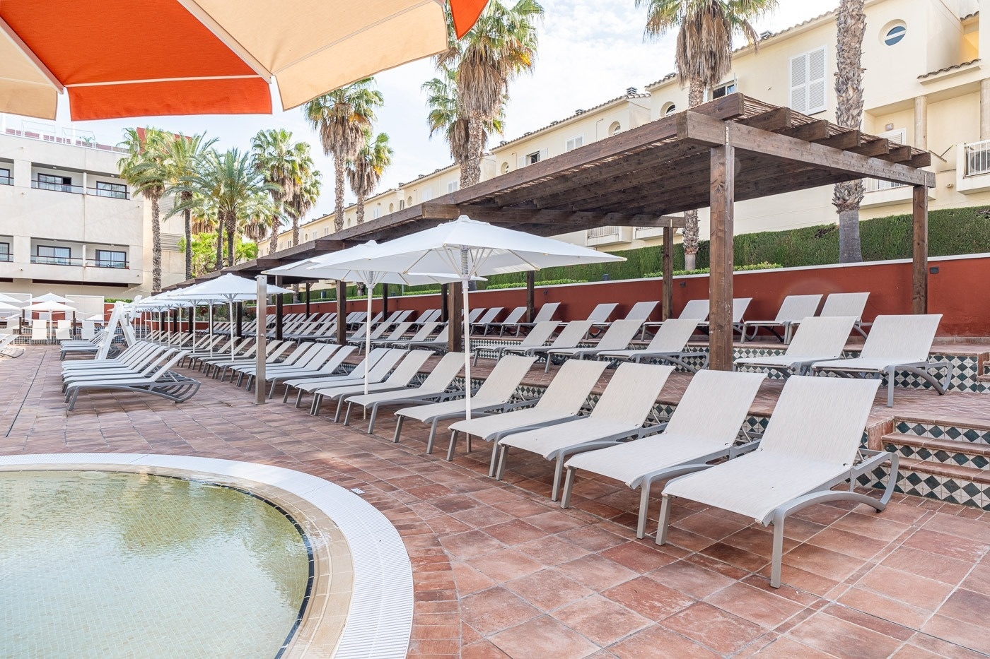 a row of lounge chairs under umbrellas next to a pool