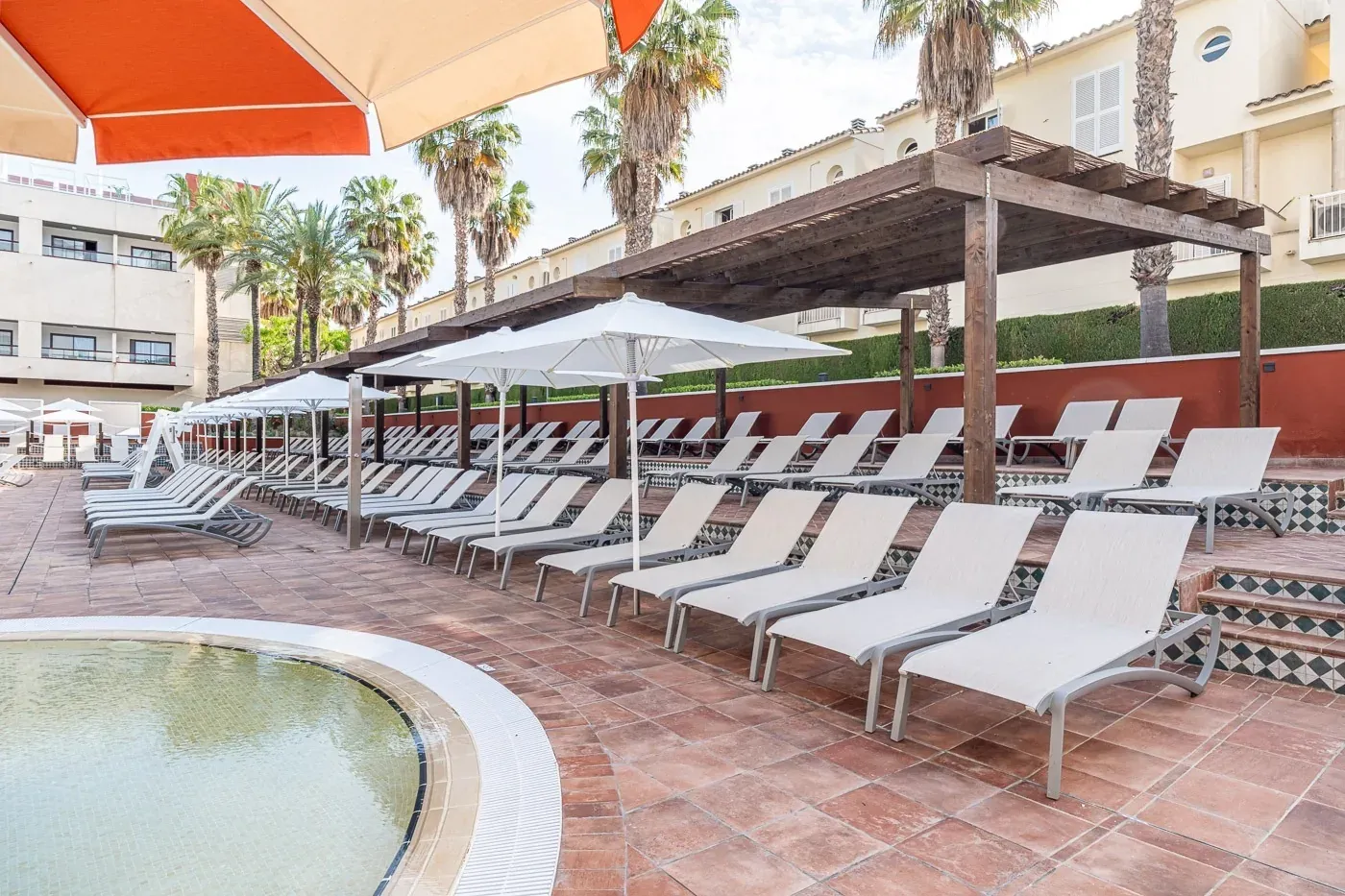ESTIVAL: Corporate, lounge chairs by pool with palm trees and buildings.