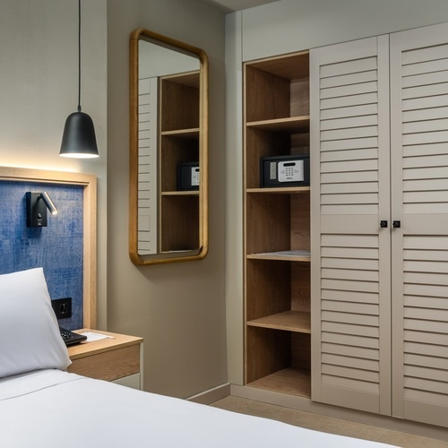 a hotel room with a bed a mirror and a safe