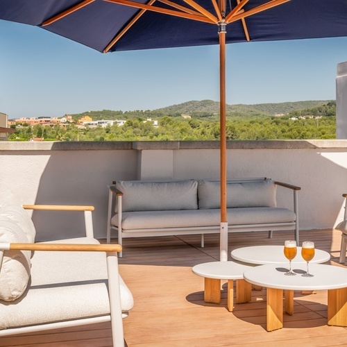 a balcony with a couch and chairs under an umbrella