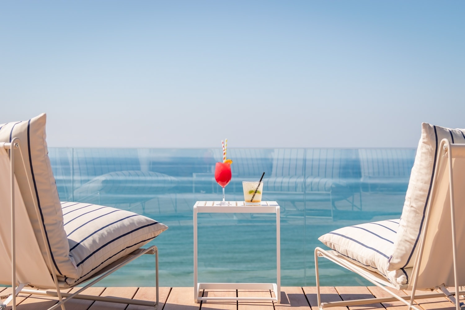 eine Frau steht neben einem Infinity-Pool mit Blick auf den Ozean