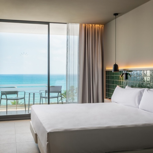 a hotel room with a large bed and a balcony overlooking the ocean