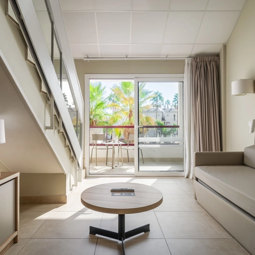 Spacious hotel room with balcony overlooking palm trees and pool. Estival Park Almaris | Estival Group | Tarragona.