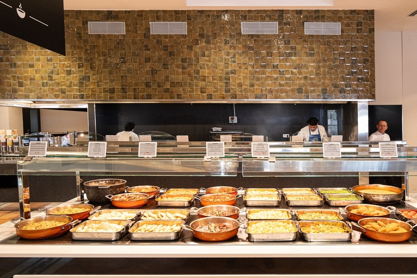 un mostrador de comida con platos de comida y un chef en la cocina