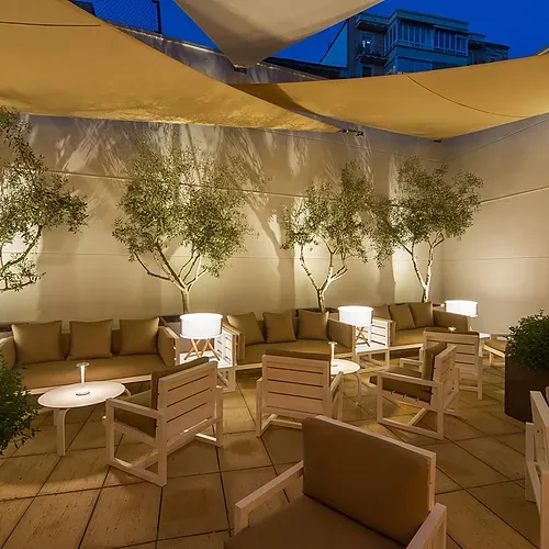 Hotel Vilamari Barcelona | Estival Group: Chic terrace seating with olive trees and modern lamps.