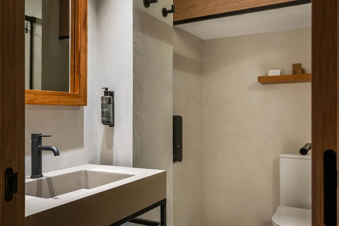 ESTIVAL: Corporativa - Lavabo de disseny modern amb aixeta negra i dispensador de sabó, adjacent a un vàter.