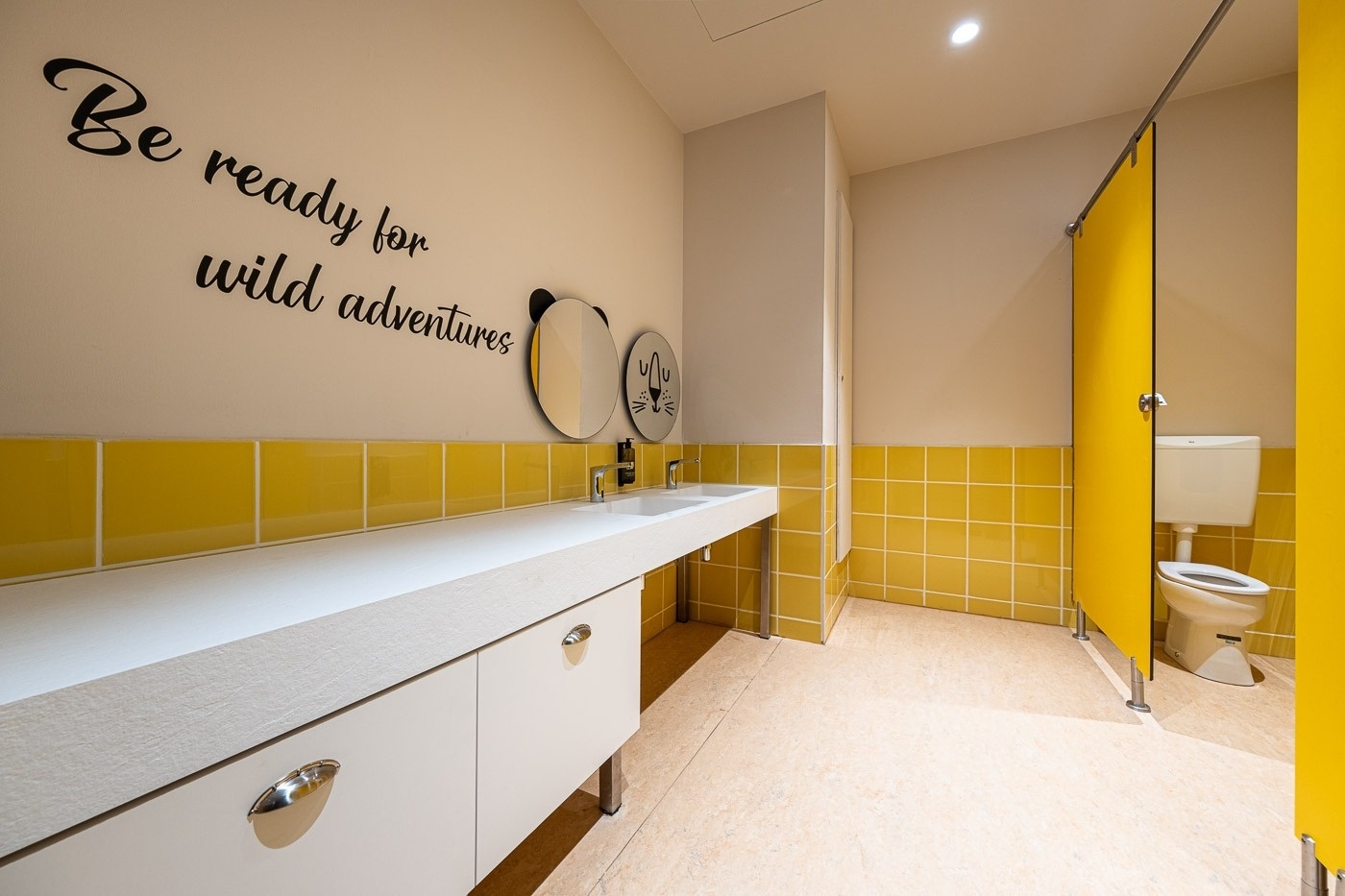 a bathroom with yellow tiles and a sign that says be ready for wild adventures