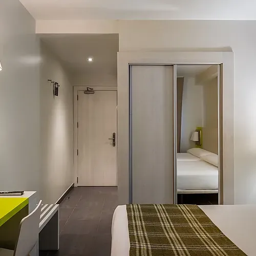 Hotel Cristina | Andorra | Estival Group: Modern room with TV, sofa, and bright green closet.