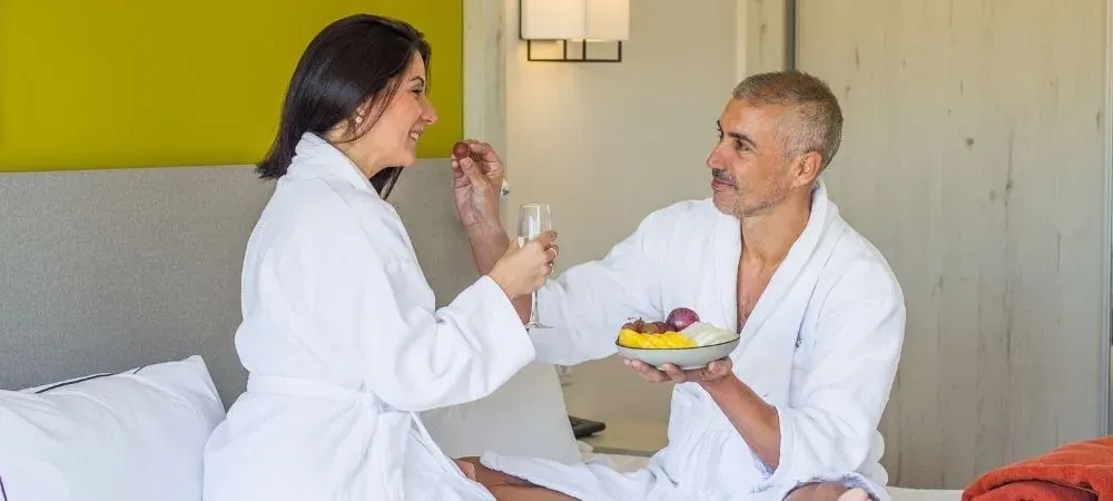 Couple savoure fruits et vin à ESTIVAL: Corporativa, en peignoirs.