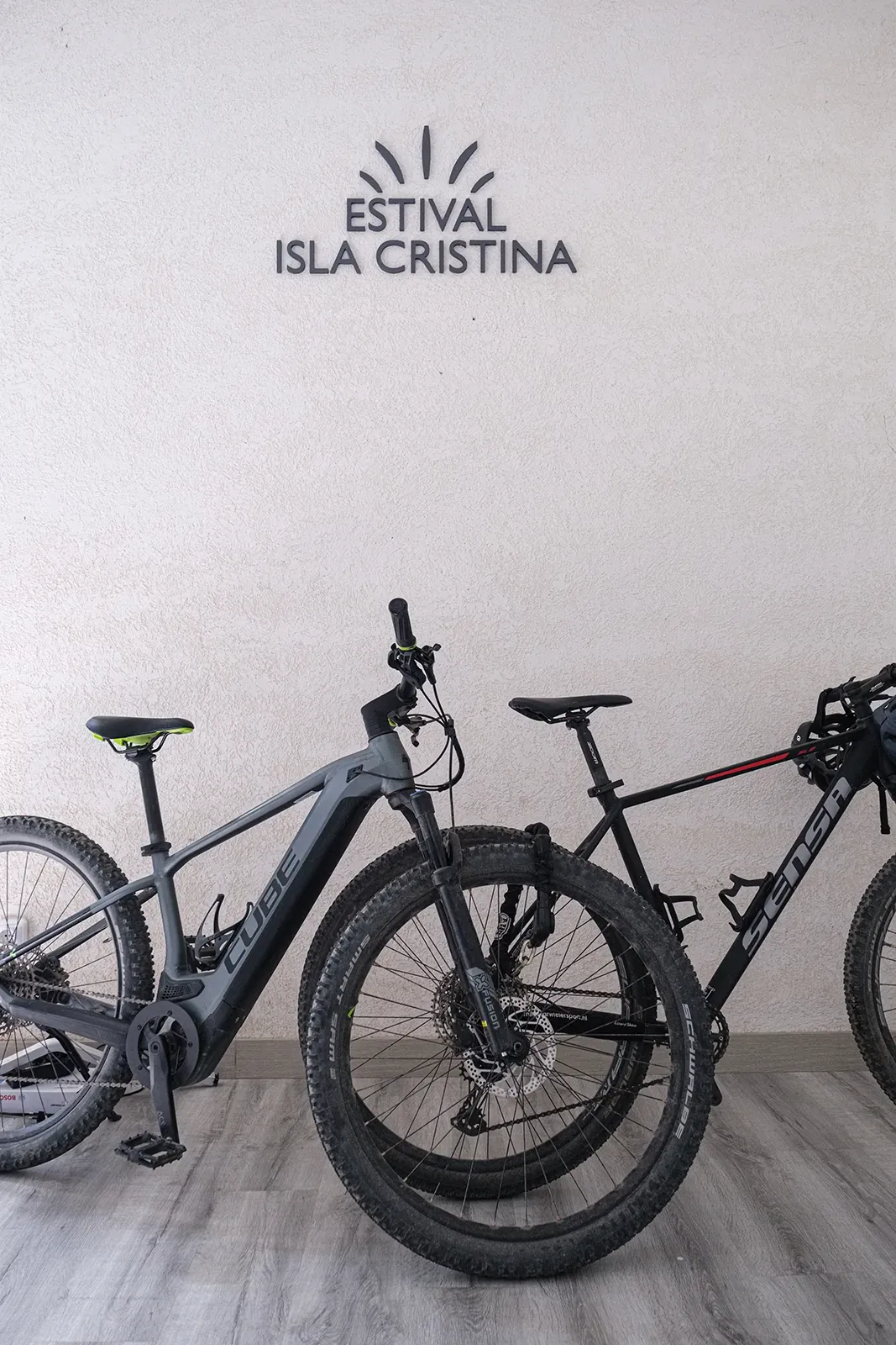 Zwei Fahrräder vor der 'ESTIVAL ISLA CRISTINA' Wanddekoration. ESTIVAL: Corporativa