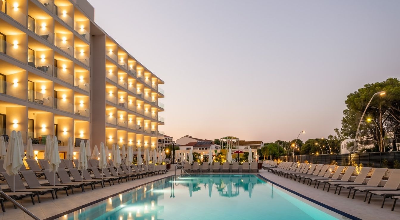 una mujer camina junto a una piscina con vistas al océano