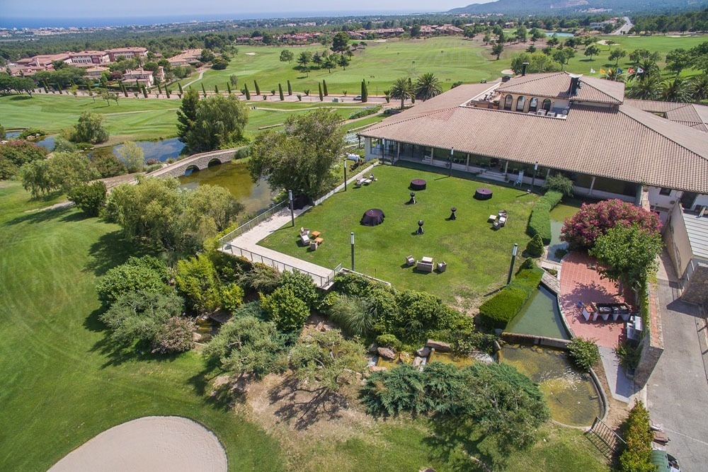 Ein Mann und eine Frau gehen mit ihren Golfausrüstungen über einen grünen Golfplatz, mit Bäumen im Hintergrund.