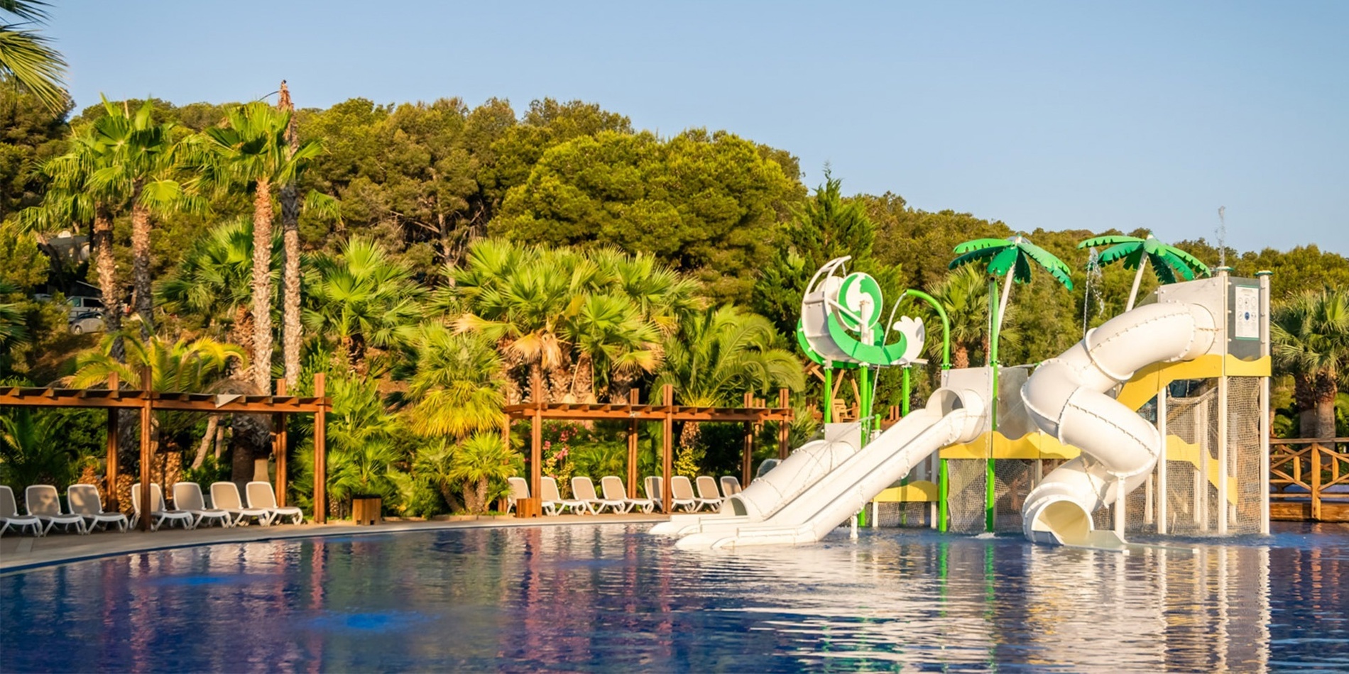 una piscina con toboganes y palmeras en el fondo