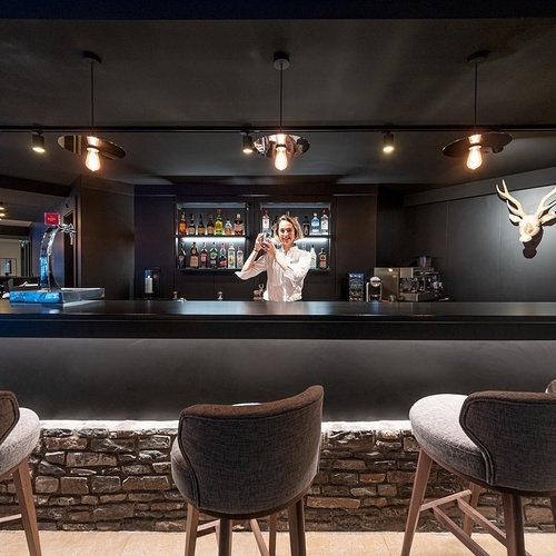 a woman standing behind a bar making a drink