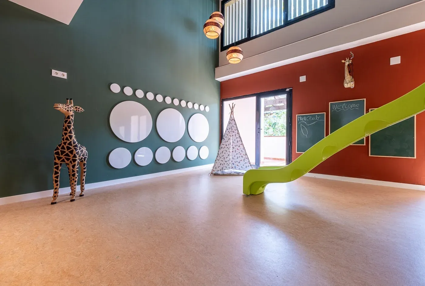 ESTIVAL: Corporate kids' play area with giraffe decor and green slide.