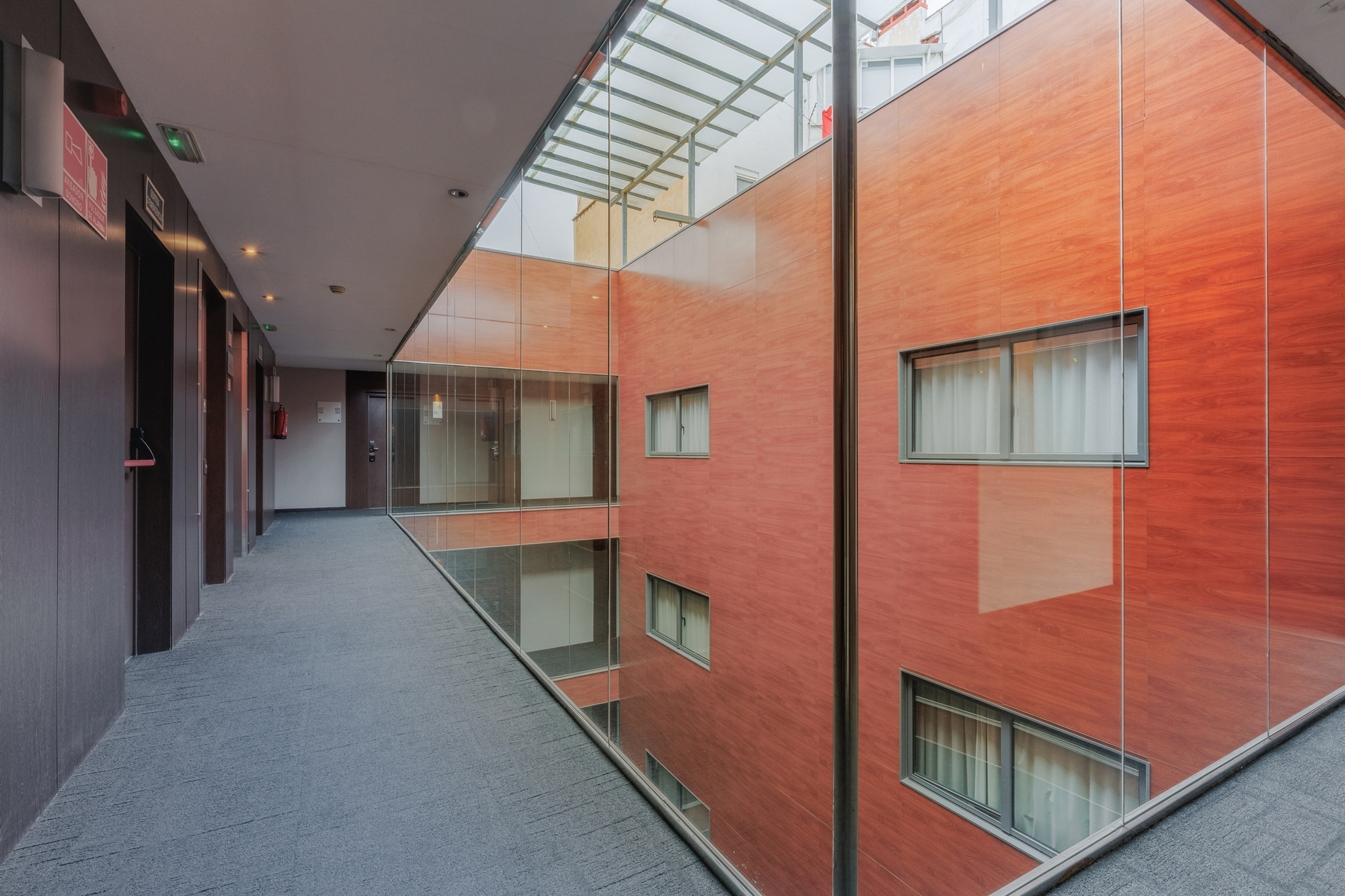 Hotel Vilamari Barcelona | Estival Group: moderner Korridor mit Glasfront und roten Ziegeln.