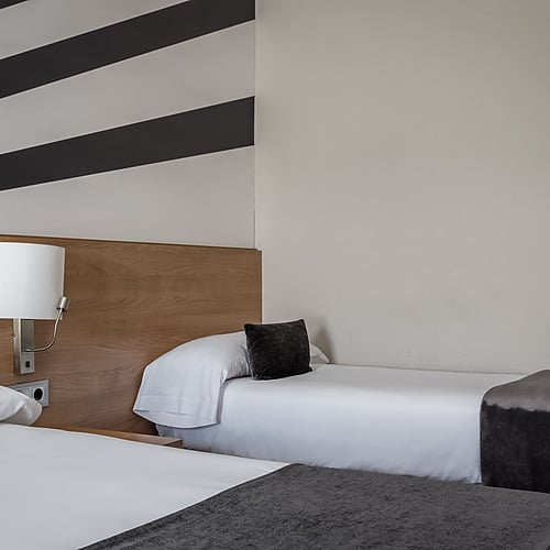 Hotel room with two beds and a desk. Book your stay at Hotel Sporting Andorra | Grandvalira Pas de la Casa.