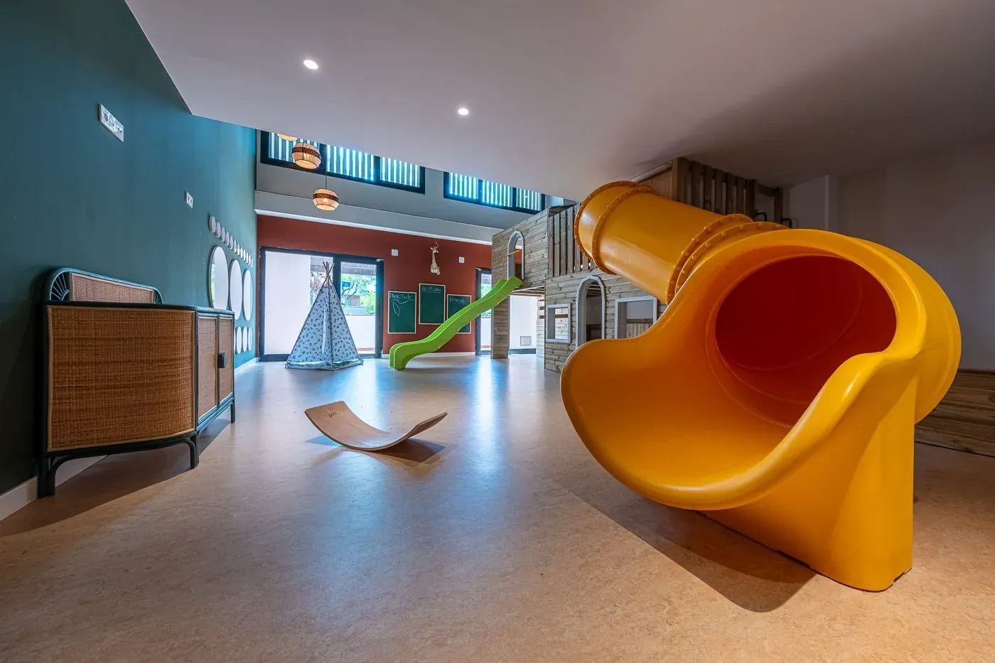 ESTIVAL: Corporate playroom with yellow slide and teepee.