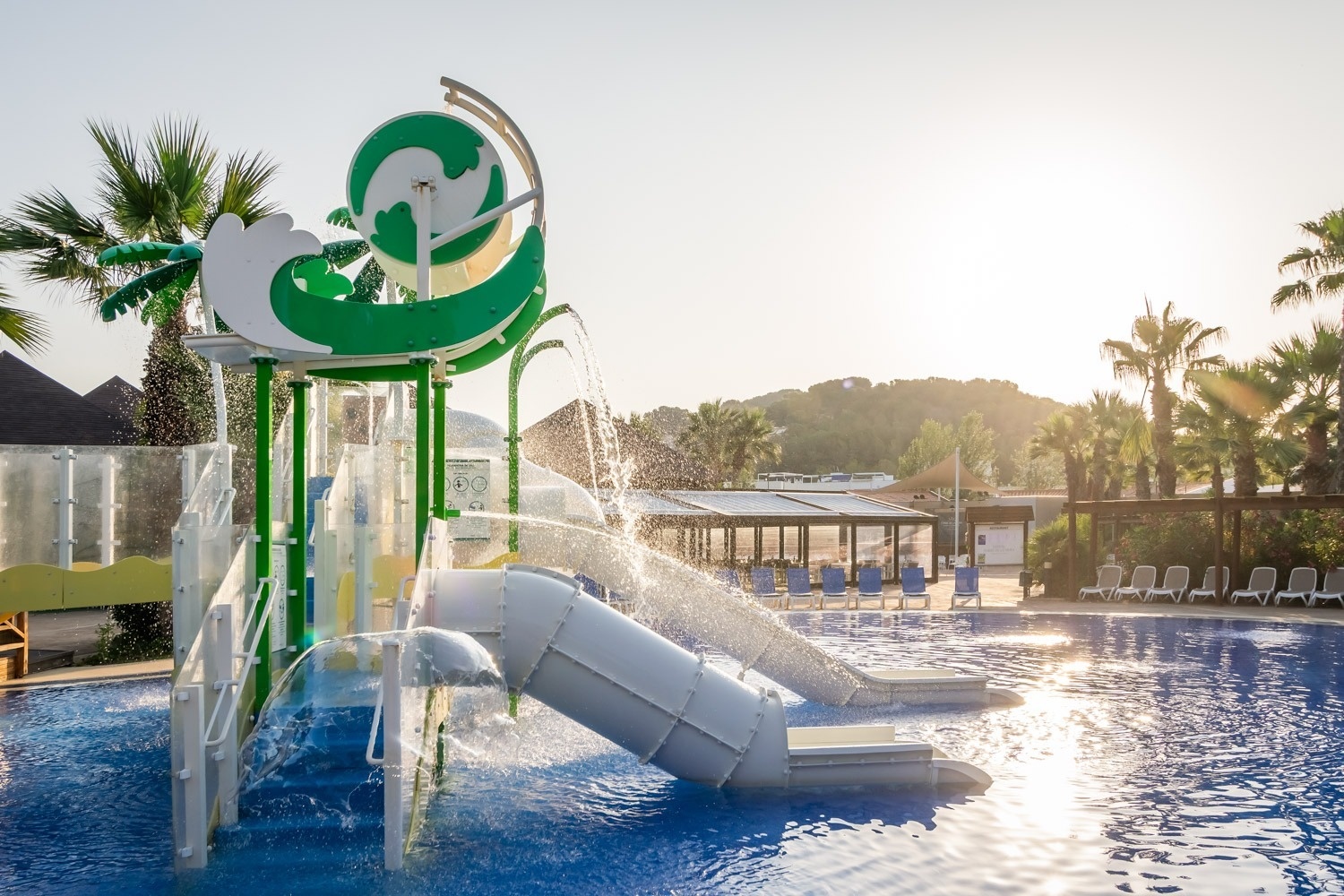 dos niños juegan en un tobogán en una piscina