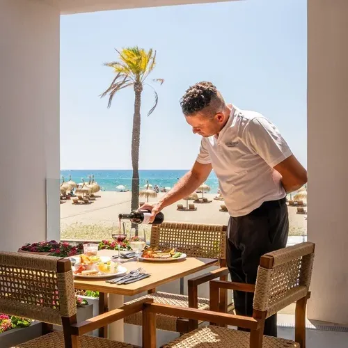 Kellner schenkt Wein an einem Tisch im Estival Maramar | Estival Group | Tarragona | Offizielle Website mit Meerblick ein.