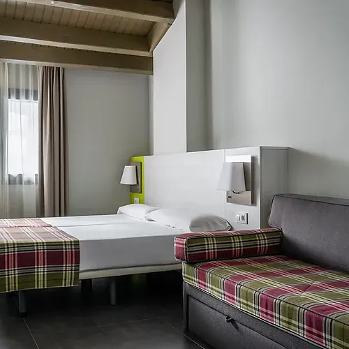 A hotel room with two beds, a sofa bed, and plaid accents. Hotel Cristina | Andorra | Estival Group | Official Web
