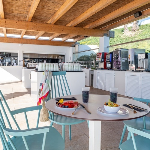a table with a bowl of fruit on it in front of a coca cola machine