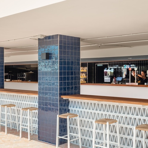 a bar with blue tiles and white stools