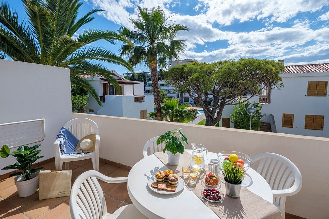 Balkon mit Tisch und Stühlen ESTIVAL: Corporativa, Blick auf Bäume und Gebäude