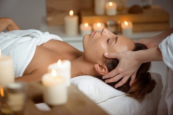 a woman is getting a head massage with candles in the background