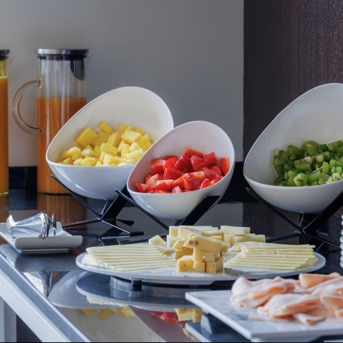 a buffet table with bowls of fruit and cheese and a pitcher of orange juice